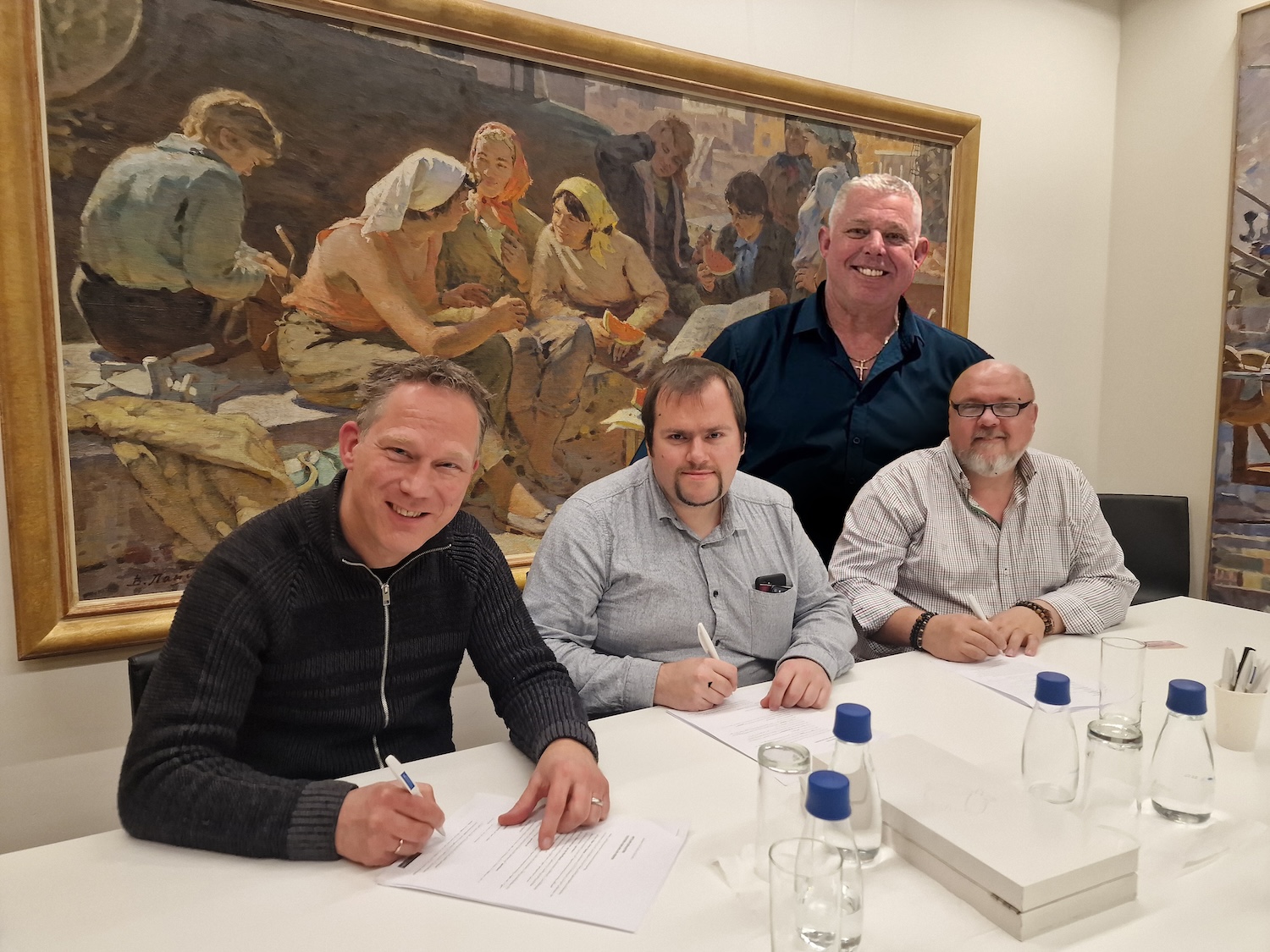 De oprichters van de stichting zetten hun handtekening op de oprichtingsovereenkomsten, zittend achter een tafel met op de achtergrond een groot schilderij