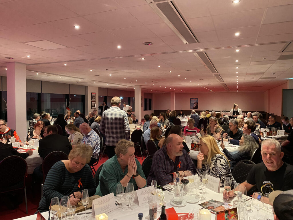 Mensen in een zaal aan tafels met drinken op de tafels